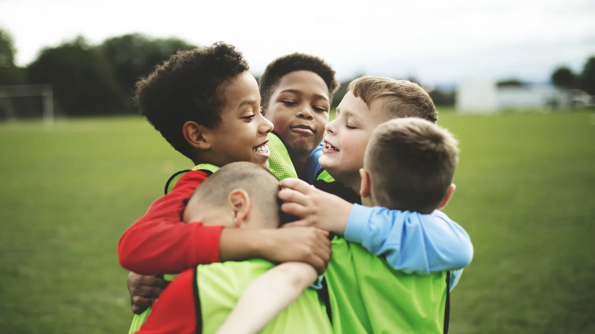 Young soccer players hugging after a game on a green field