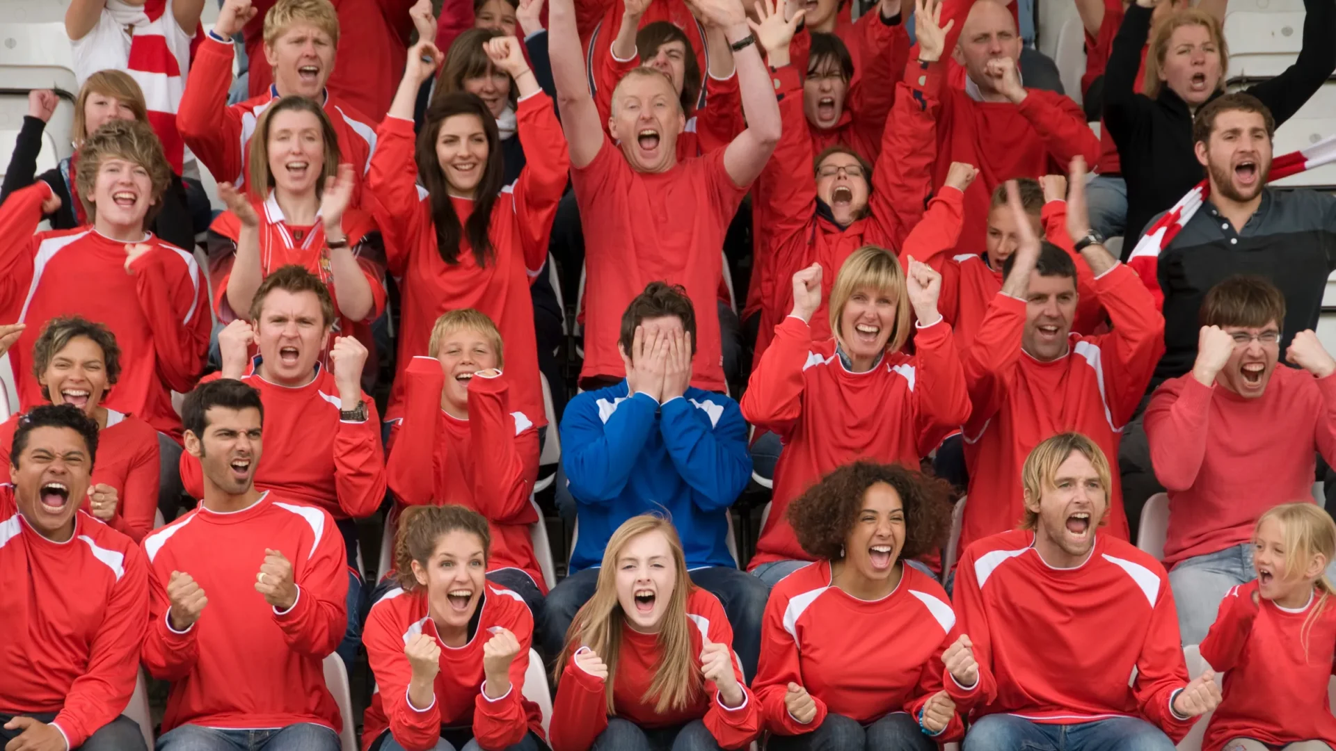A crowd of fans in red cheering their team in a stadium