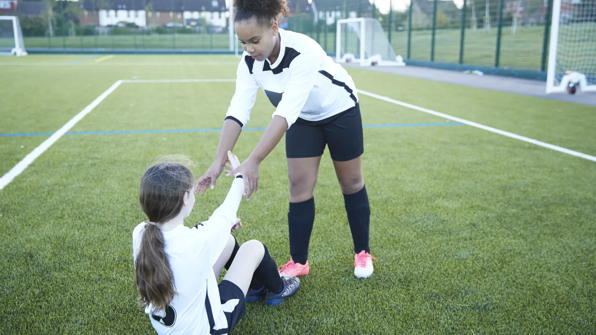 A young soccer player offering a hand to help an opponent up